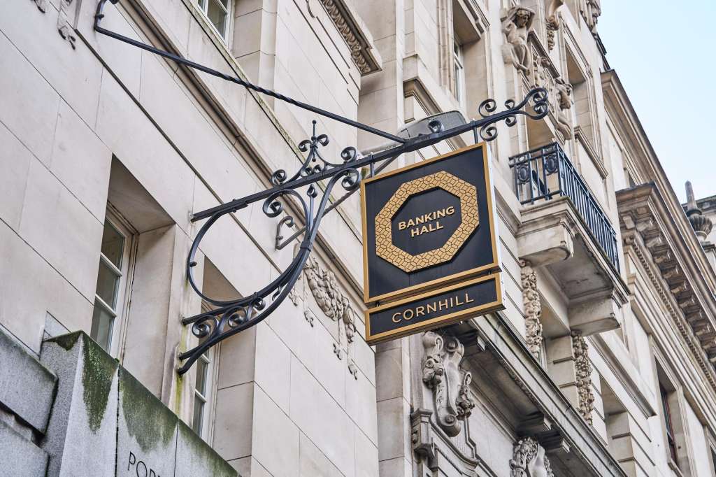 Exterior facade of historic stone building with ornate wrought-iron signage bracket and Banking Hall nameplate.
