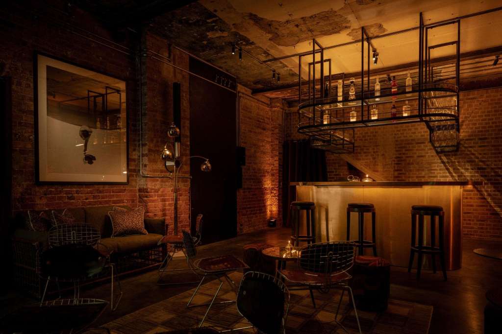 Industrial brick room with bar counter, modern seating, and warm ambient lighting from overhead fixtures.