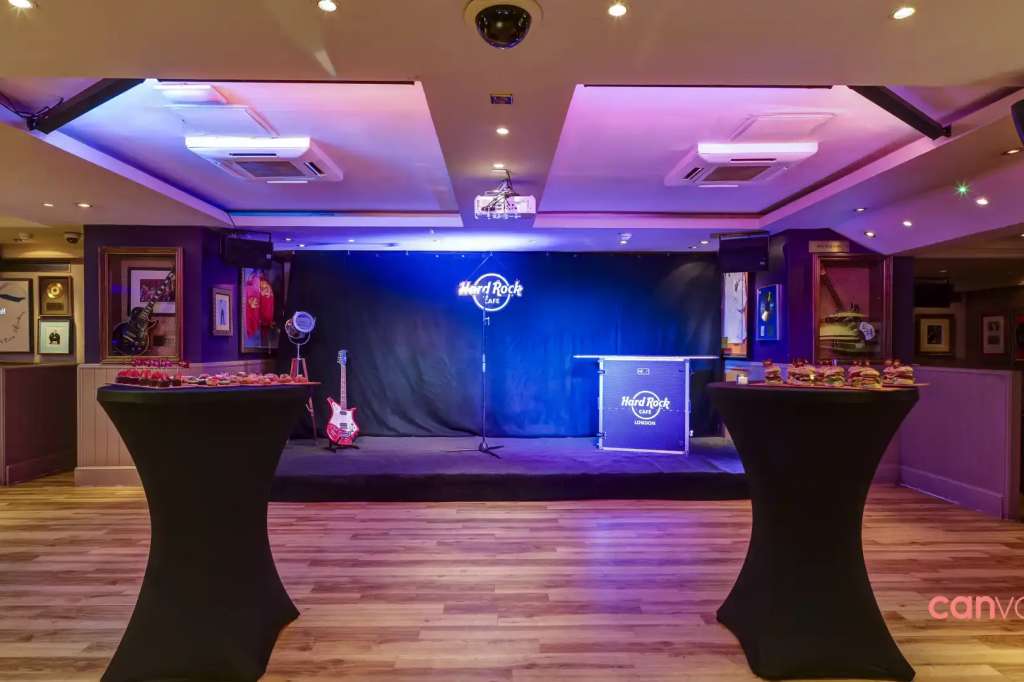 The Rock Room set up for an event with stage, neon signage, purple ambient lighting, and high-top tables.