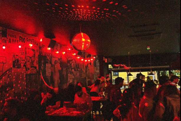 Interior venue with red ambient lighting, decorative lanterns, and guests mingling in atmospheric setting.
