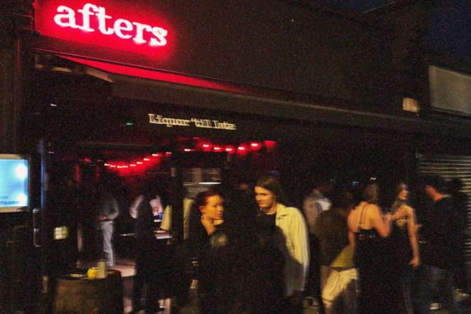 Exterior storefront of Afters venue at night with red neon signage and guests gathered outside.