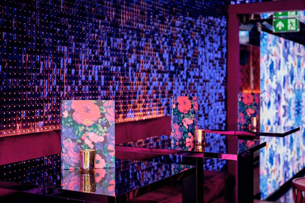 Modern event space with LED pixel wall displays, floral branded signage, and burgundy architectural elements.
