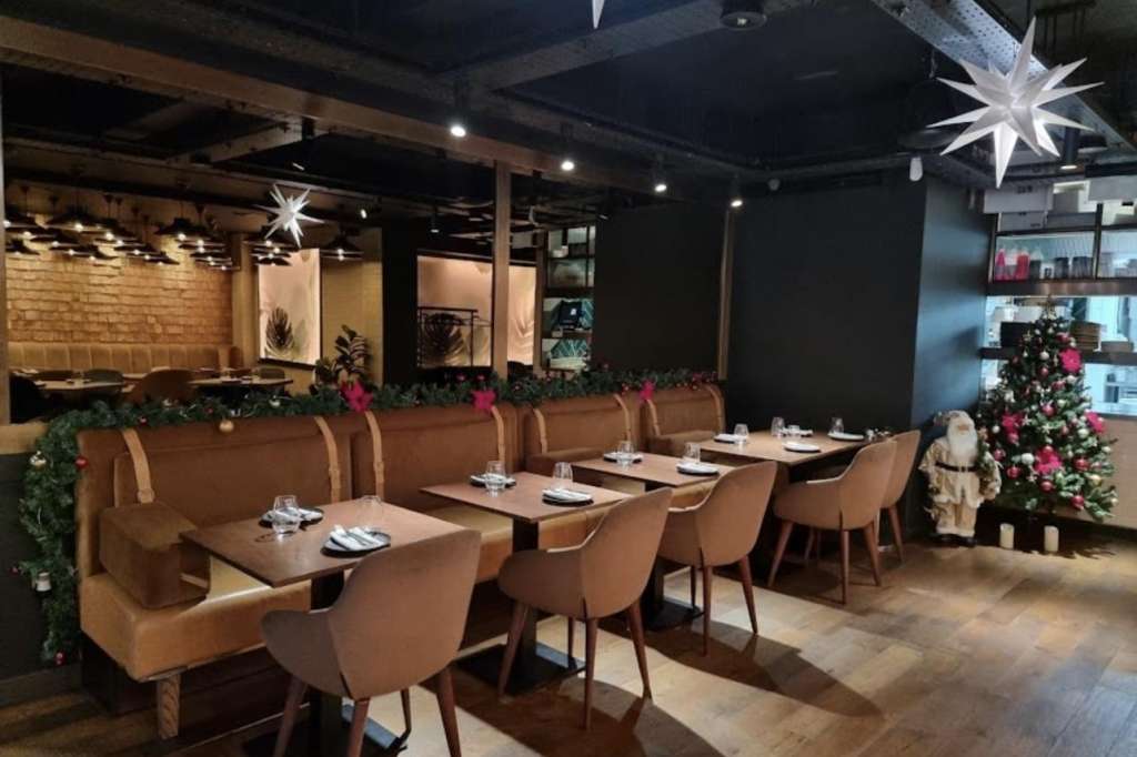 Private dining room with banquette seating, place settings, and festive garland and star decorations.