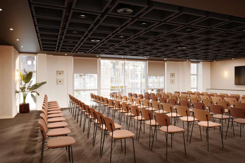 Conference room with rows of tan chairs facing a screen, modern ceiling, and floor-to-ceiling windows.