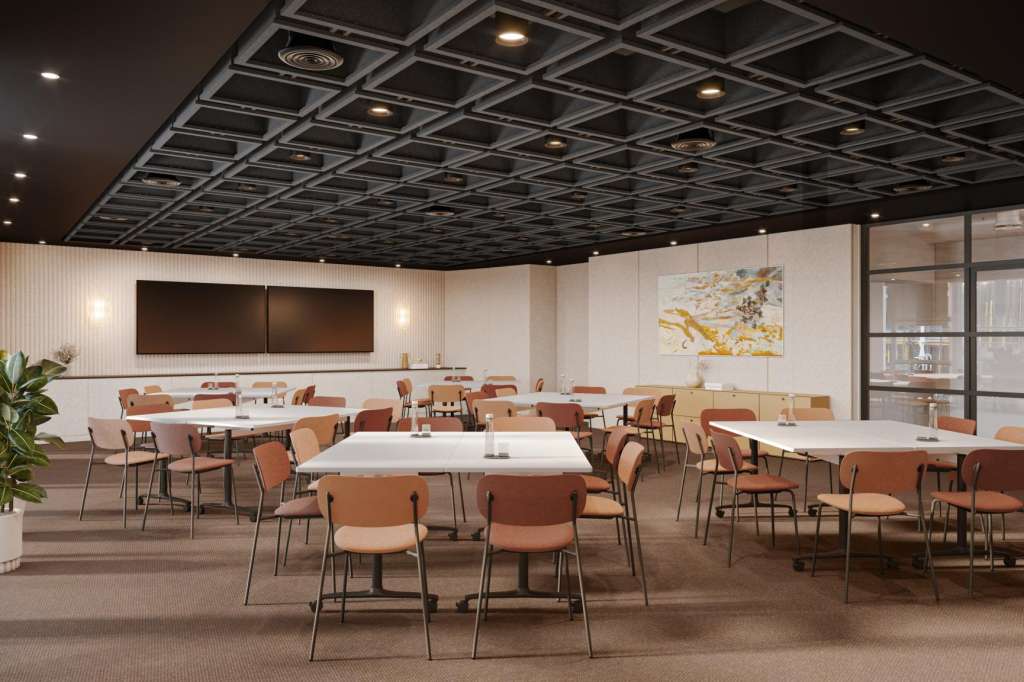 Modern conference room with multiple round tables, orange chairs, gridded ceiling, and wall-mounted screens.