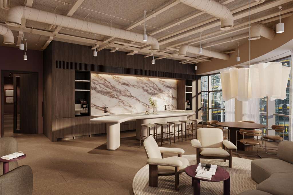 Modern open-plan space with kitchen island, bar seating, lounge furniture, and floor-to-ceiling windows overlooking city skyline.