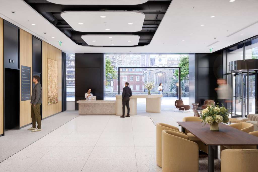 Modern conference space with reception desk, seating areas, floor-to-ceiling windows overlooking cityscape, and contemporary lighting.