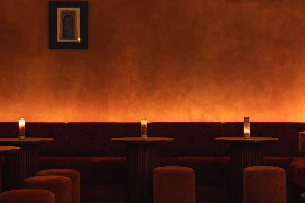 Modern lounge with terracotta walls, framed artwork, upholstered seating, and ambient lighting.
