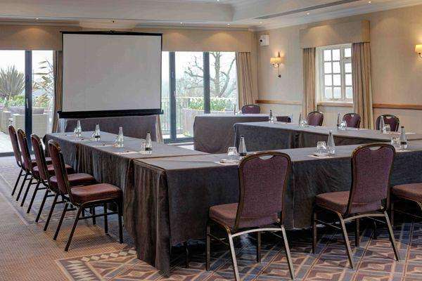 Windmill Suite set up with U-shaped table configuration, projection screen, and theater-style seating for a conference.