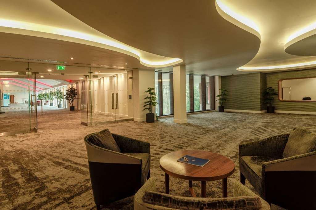 The Ballroom empty with curved ceiling lighting, lounge seating, and glass partition walls.