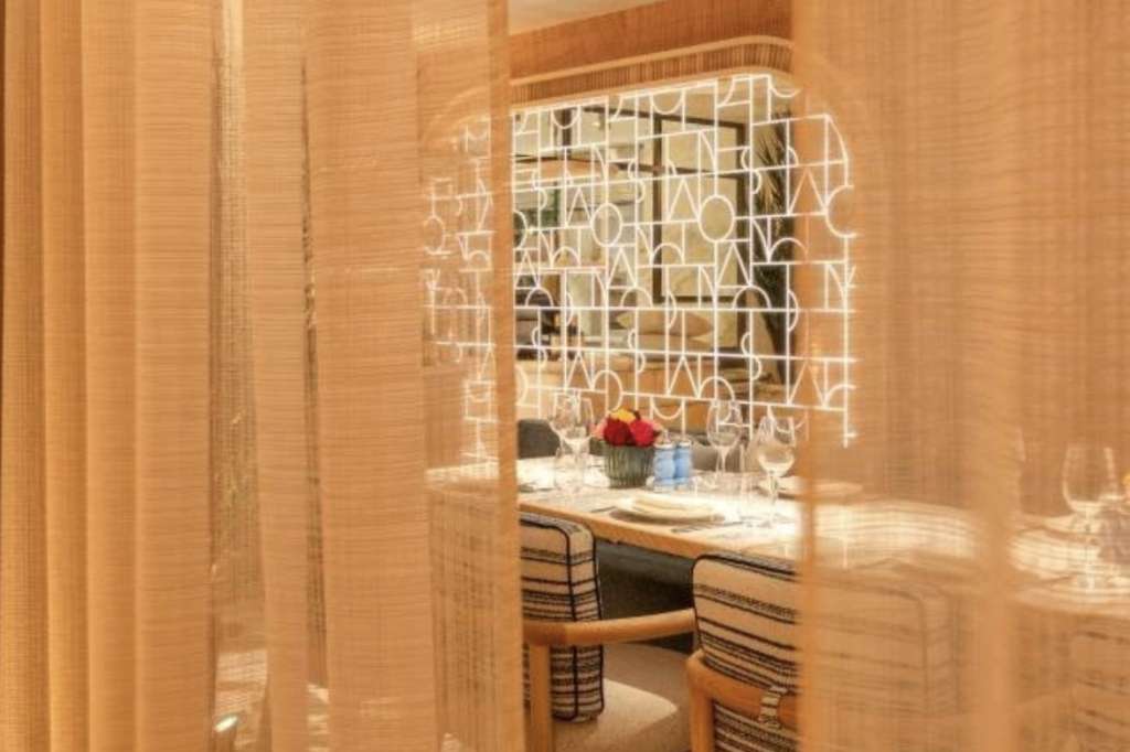 Private dining room with intimate table setting, decorative white lattice screen, and warm wood paneling.
