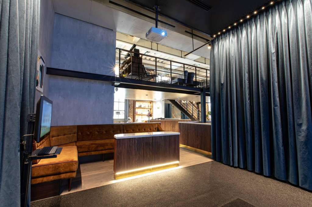 Modern interior with two-level mezzanine, bar counter, leather seating, and ambient lighting.