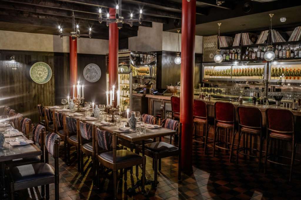 Main Restaurant set for seated dinner with long table, place settings, candelabras, and bar visible in background.