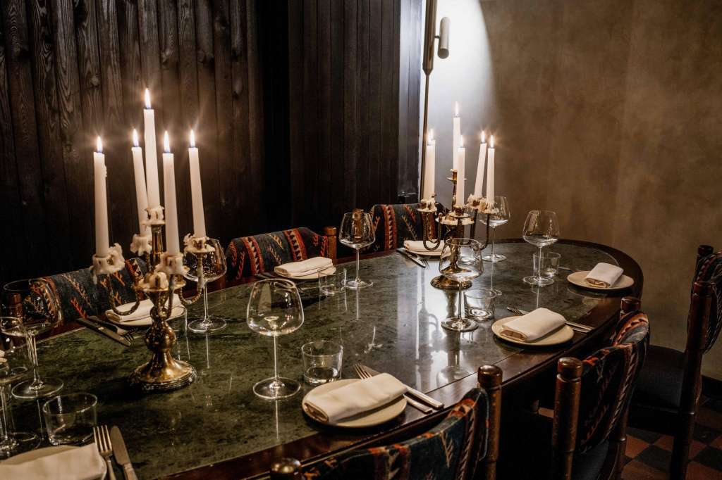 Wine Bar set for formal dining with long table, candlelit candelabras, wine glasses, and patterned chair runners.