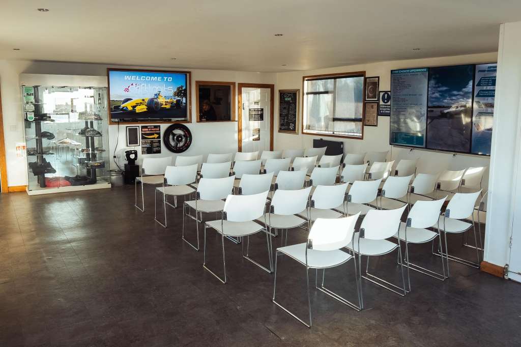 Open room with rows of white chairs facing a screen displaying welcome message and automotive imagery.