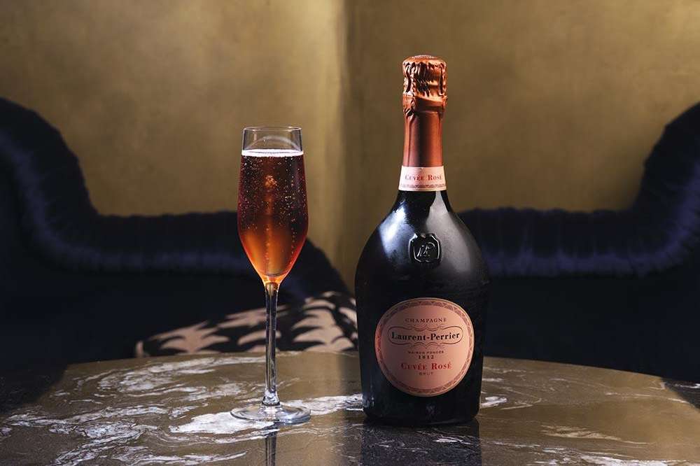 Champagne bottle and flute on marble table in lounge bar with warm ambient lighting.