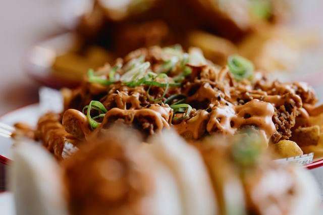 Close-up of plated Asian dumplings with meat filling and green onion garnish on red-rimmed plate.
