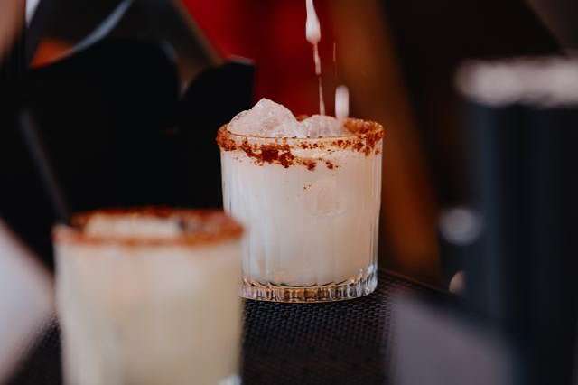 Bartender pouring cocktail into glass with spiced rim and ice.