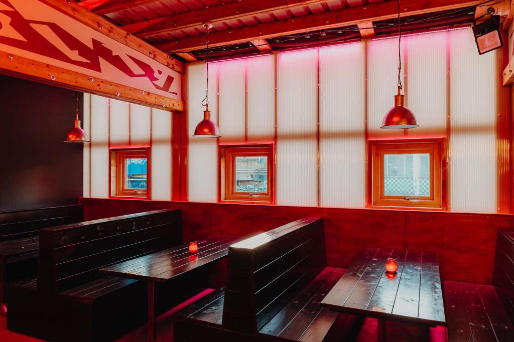 Hotel Milano Bar with red and white industrial design, booth seating, pendant lighting, and framed windows.