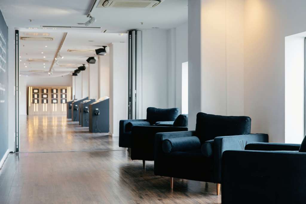 Modern corridor with black velvet seating, polished concrete floor, track lighting, and minimalist architectural details.