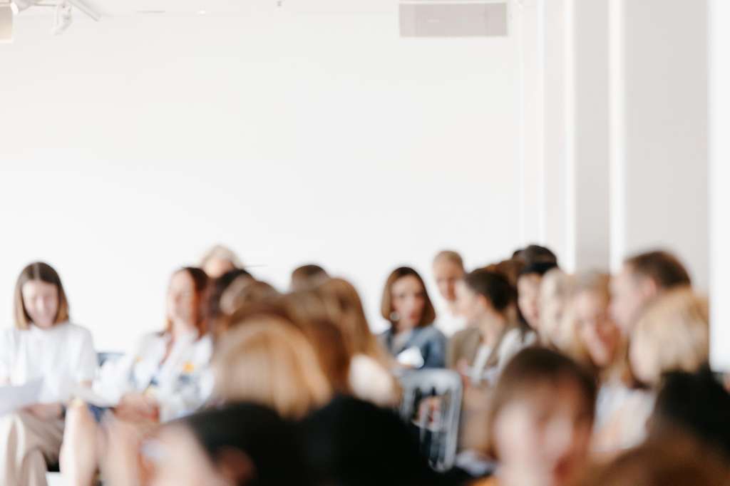 Group of people gathered in a bright, minimalist white room with natural lighting and modern architecture.