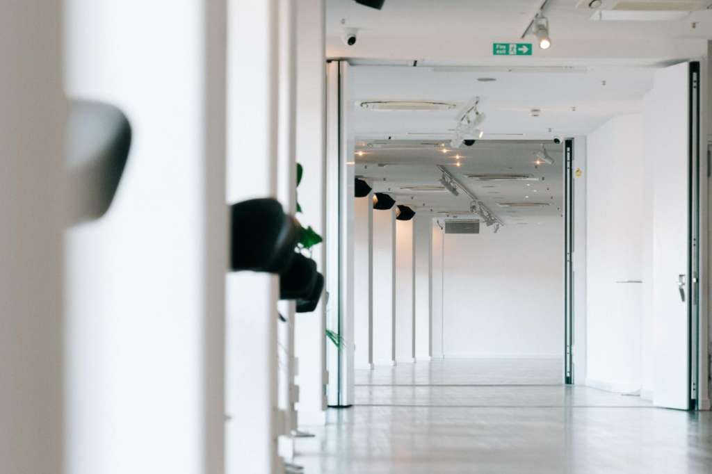Empty gallery space with polished concrete floor, white walls, track lighting, and modern architectural features.