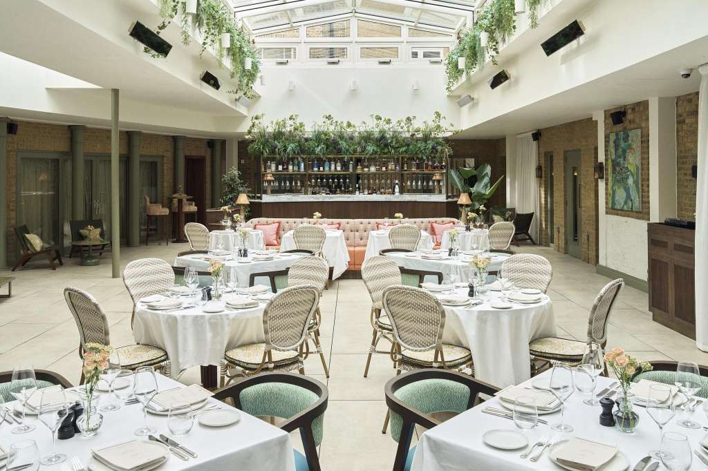 The Dining Room set up for a formal dinner with round tables, white linens, place settings, and a bar backdrop.