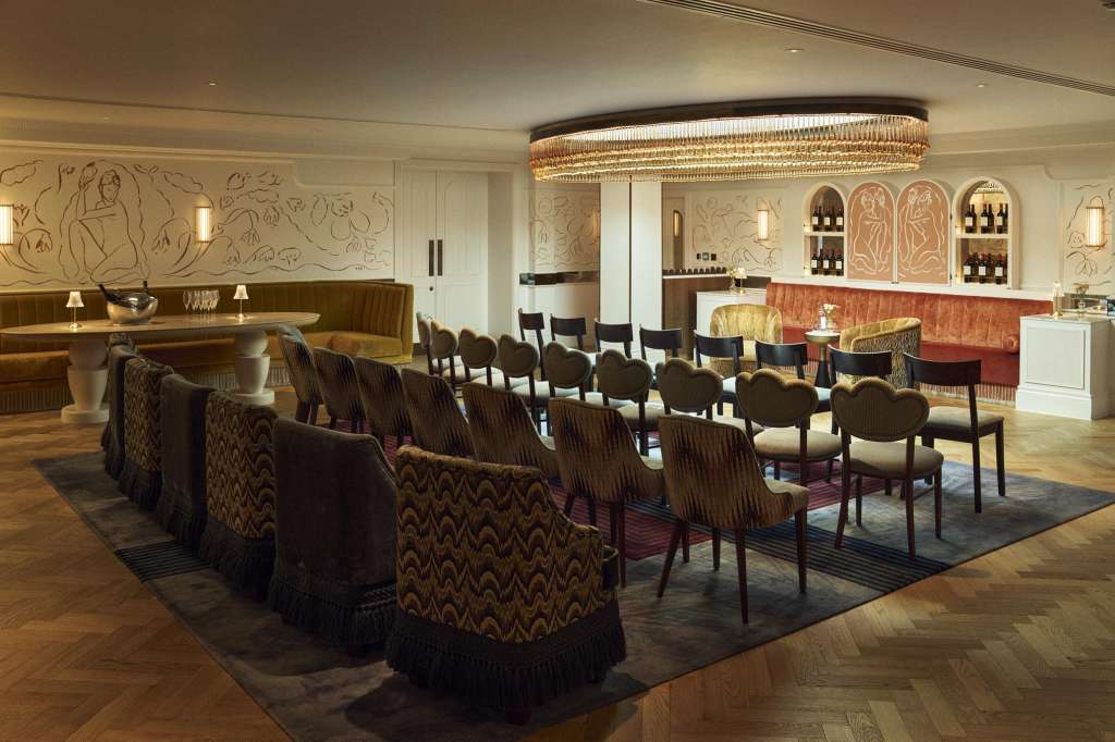 Elegant lounge with rows of upholstered chairs arranged in theater-style seating, bar counter, and decorative wall panels.