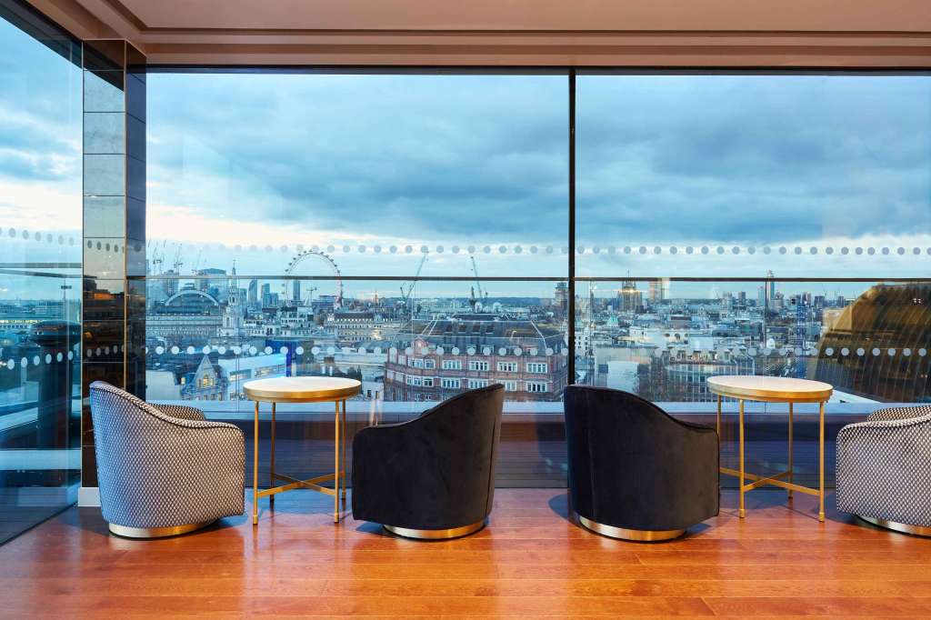 Rooftop lounge with panoramic London skyline views, modern seating, and floor-to-ceiling windows.